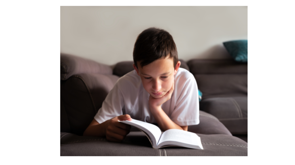 A boy reading on a couch in the summer.